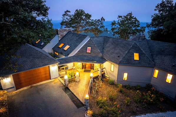 A residential area with multiple houses, each featuring a garage, a wooden deck, and a stone pathway leading to the entrance.