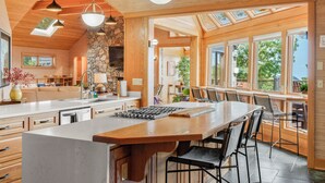 Una cocina amplia con una isla grande, vigas de madera y un revestimiento de piedra.