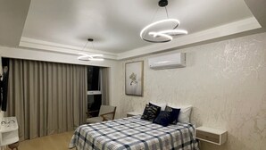 A modern bedroom with a large bed, a desk, and a chair.