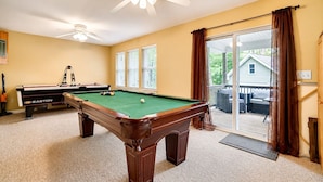 A pool table in a room with a ceiling fan, a window with blinds, and a view of a house through a sliding glass door. - Serenity Cottage Deck, Game Room & Fire Pit near Narrowsburg Masthope (Lackawaxen)
