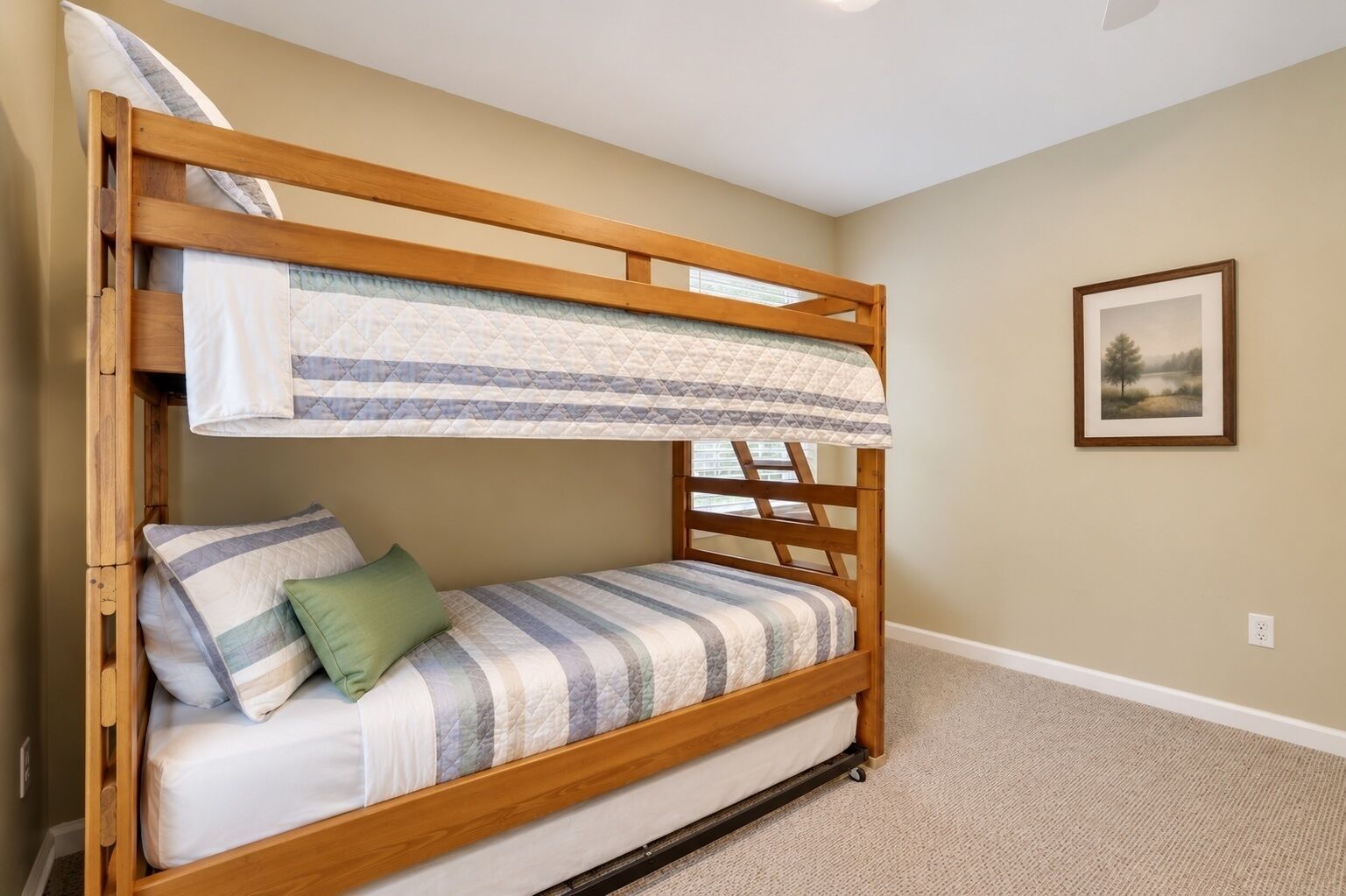A bunk bed with a quilted top and bottom, a pillow, and a wall-mounted picture.
