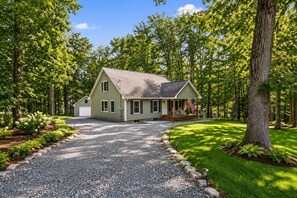 A two-story house with a porch, a driveway, and a well-maintained lawn.