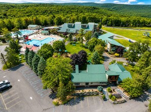 A resort with a swimming pool, multiple buildings, and a parking lot.