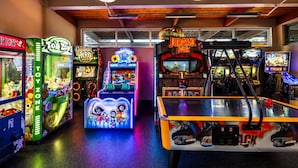 A gaming arcade with various machines, including claw games and racing games. - Serenity Cottage Deck, Game Room & Fire Pit near Narrowsburg Masthope (Lackawaxen)