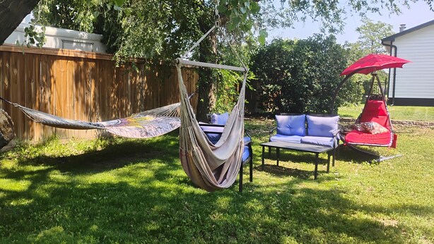 A hammock, a red umbrella, and a blue sofa in a backyard. - Sweet Rushmore Suite (Rapid City)