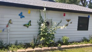 A white house with a window, a butterfly decoration, and a plant growing against the wall. - Sweet Rushmore Suite (Rapid City)