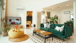 Una sala de estar moderna con un sofá verde, un sillón de peluche amarillo y un televisor de pantalla plana.