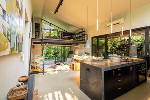 Een moderne keuken met een groot schiereiland, inbouwapparatuur en uitzicht op weelderige begroeiing.