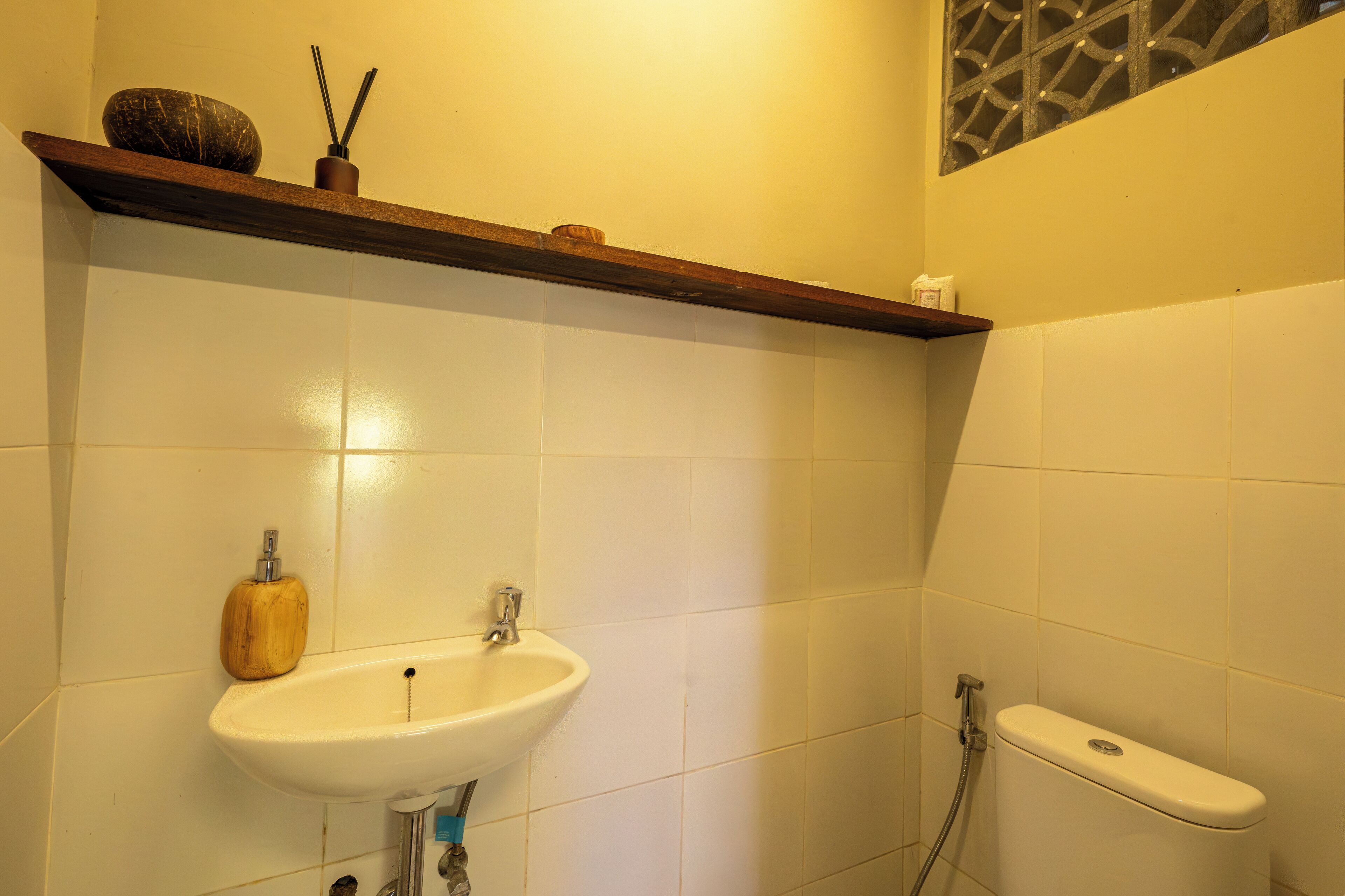 Een badkamer met een wit wastafel, een houten plank en een toilet.