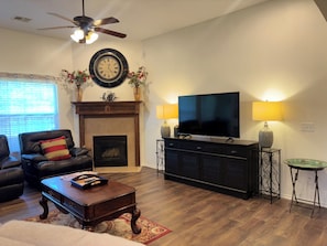 A living room with a fireplace, a television, and a ceiling fan. - Heart of Edmond Retreat - 3bed 2bath (Edmond)