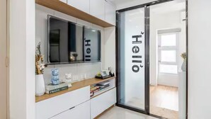 Ein modernes Hotelzimmer mit einem großen Spiegel, einem Flachbildfernseher und einer Glastür mit dem Namen des Hotels.