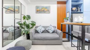 Ein modernes Wohnzimmer mit einem grauen Sofa, einem Couchtisch und einem Essbereich mit einem blauen Schrank.