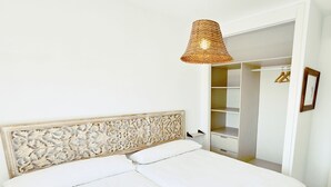 A bedroom with a bed, a decorative headboard, a hanging light fixture, and a walk-in closet.