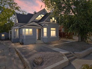 A two-story house with a front porch, a garage, and a driveway. - East Street Retreat | Walk Everywhere! (Salt Lake City)