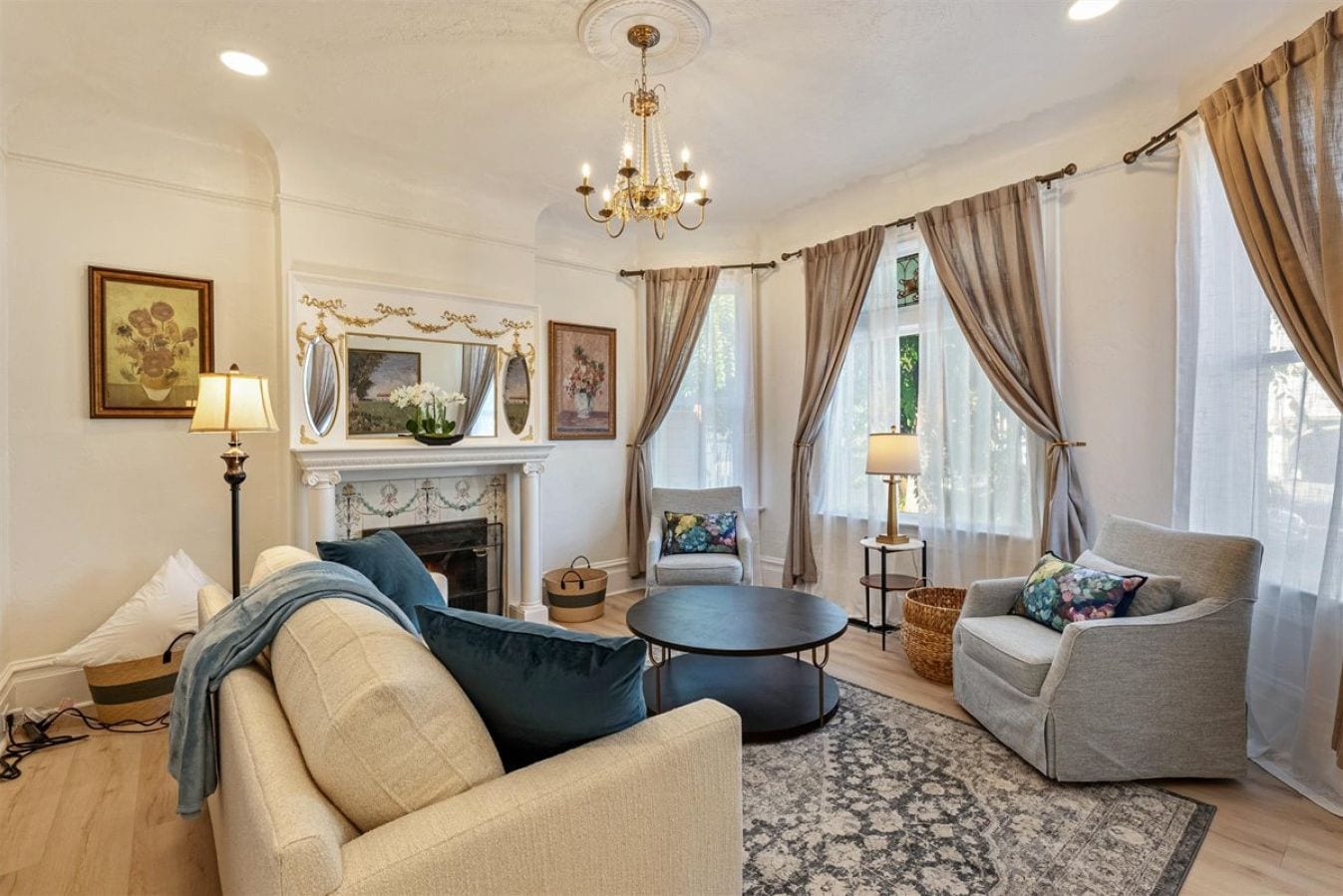 A living room with a fireplace, two sofas, a round coffee table, and a chandelier.
