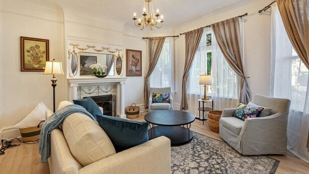 A living room with a fireplace, two sofas, a round coffee table, and a chandelier.