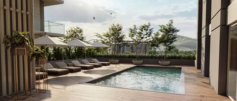 Un área de piscina exterior moderna con sillas de descanso y sombrillas, rodeada de plantas en macetas y vistas a edificios distantes.
