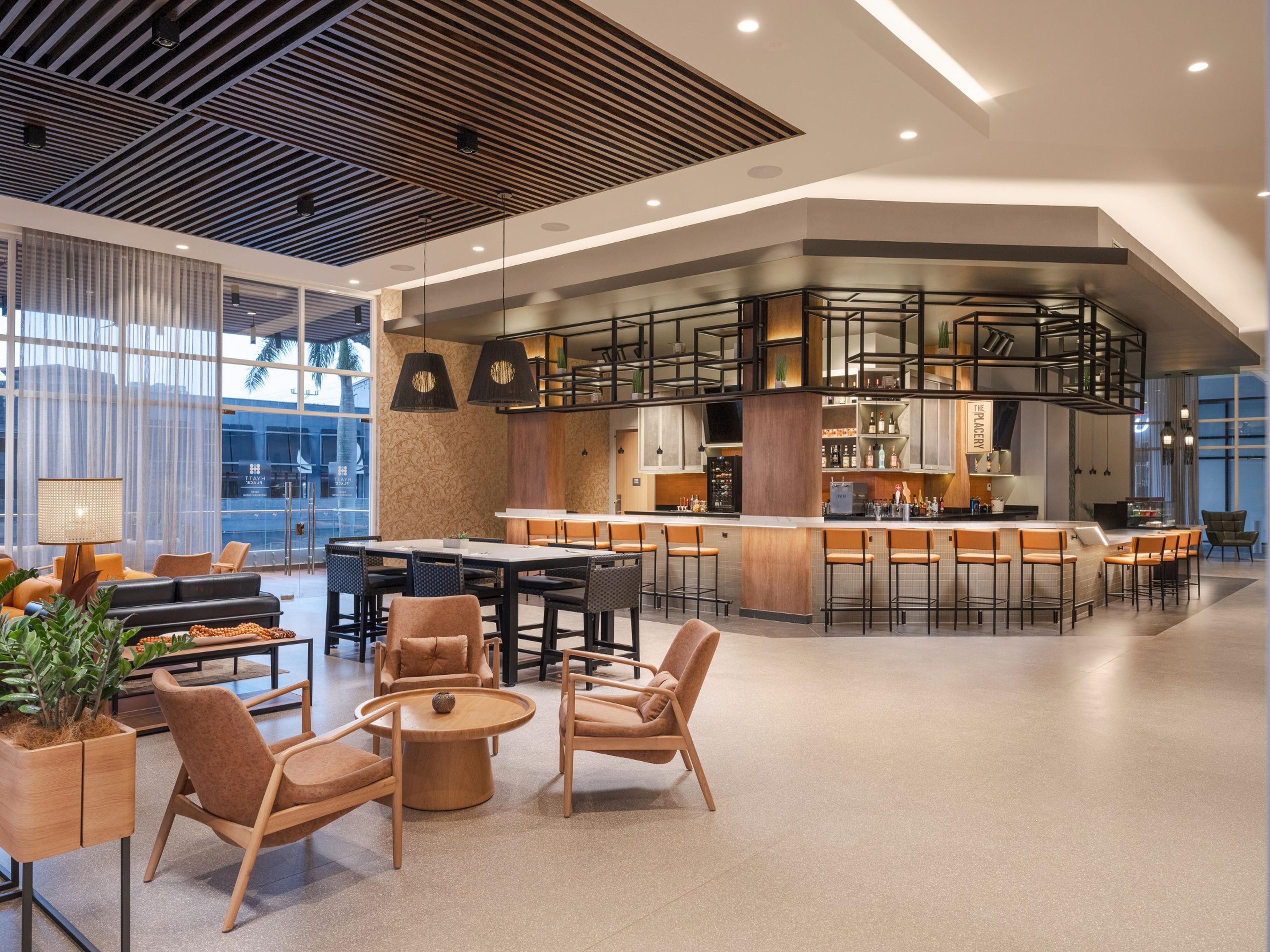 Un intérieur moderne avec un bar, des espaces pour s’asseoir et une vue dégagée grâce à de grandes fenêtres.