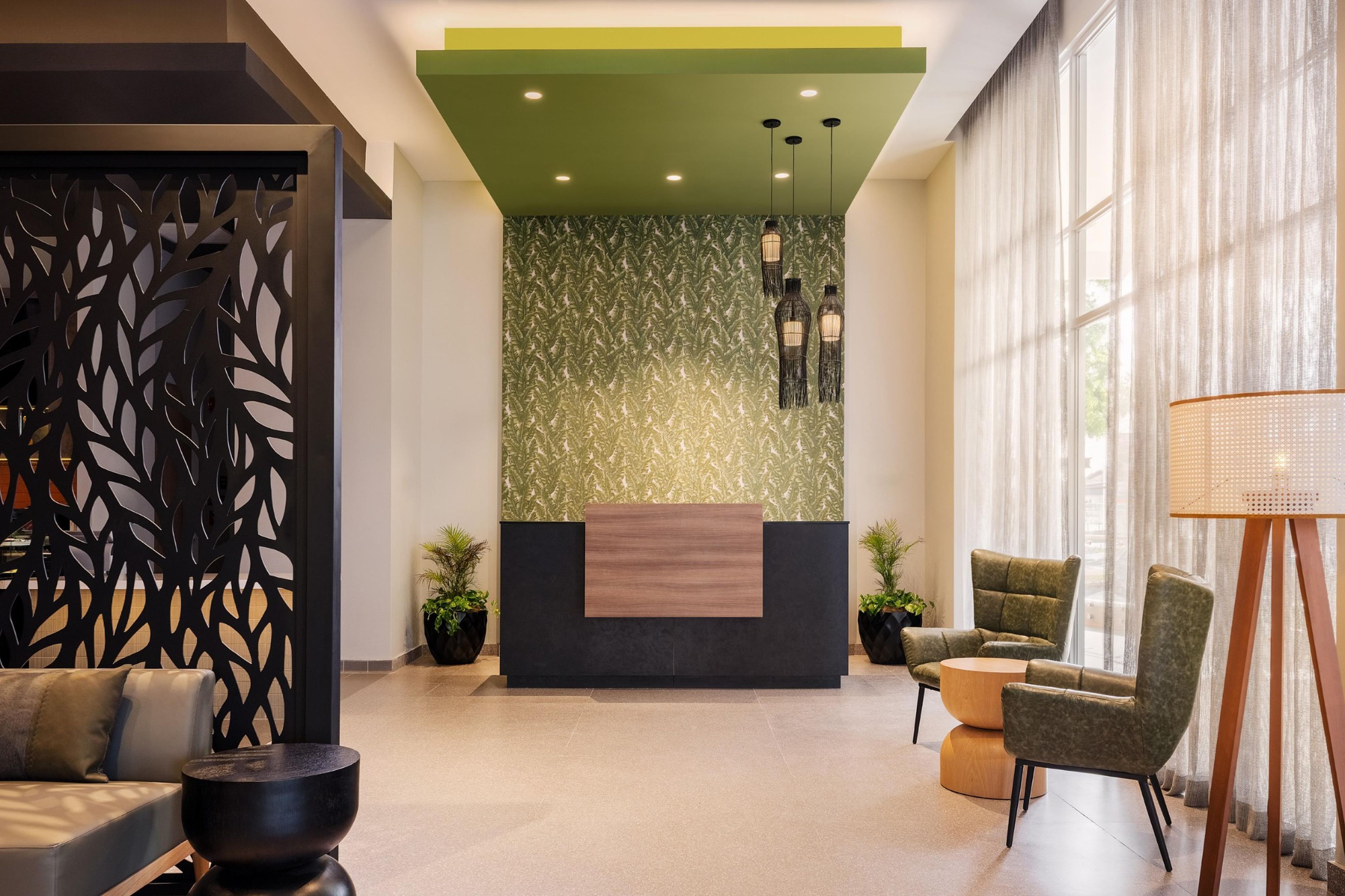 A reception area with a green accent wall, a reception desk, seating, and a large window.