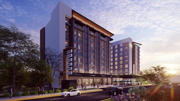Un hotel moderno con varios pisos, entrada cubierta y diversas comodidades, incluyendo restaurantes, una óptica y una farmacia.