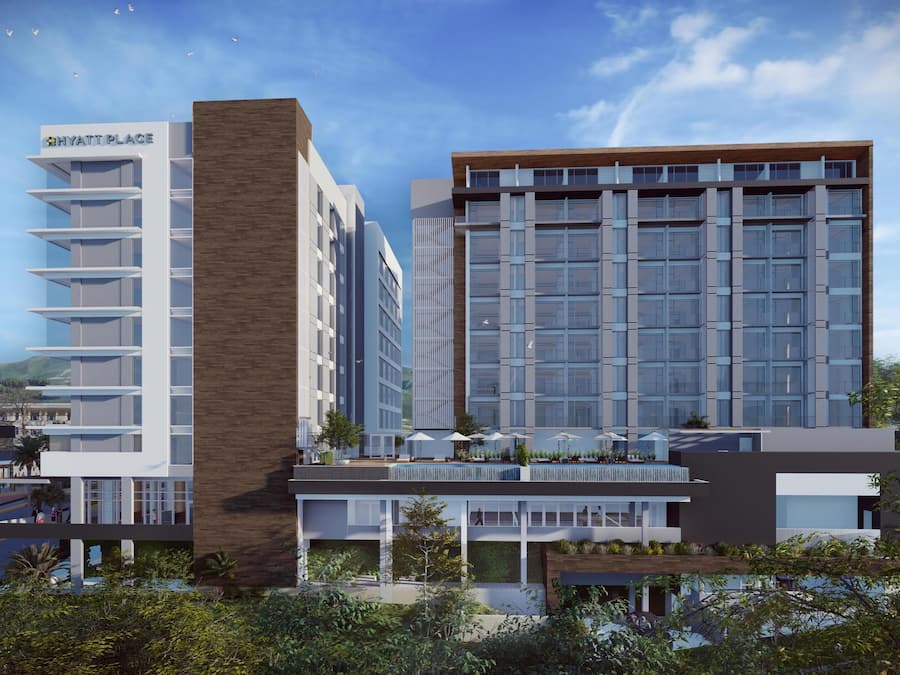 A modern hotel with a prominent 'HYATT PLACE' sign, multiple floors, and a rooftop terrace with outdoor seating.