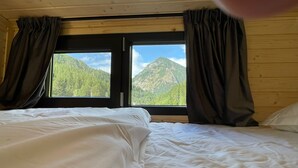 Una habitación con dos camas, una ventana con cortinas y vistas a montañas.