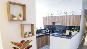 Moderni keittiö, jossa on puiset kaapit, keskellä oleva keittiösaareke ja ruukkukasveja.