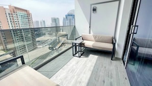 A modern balcony with a sofa and a small table, offering a city view.