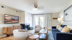 A living room with a TV, fireplace, sofa, armchairs, and a coffee table.