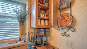 Une cuisine équipée d’une machine à café, agrémentée d’une plante en pot et ornée d’assiettes décoratives au mur.