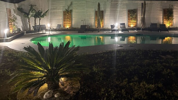 A nighttime pool area with lounge chairs and wall-mounted lights. - B&B Villa Gabry  (Capo d'Orlando)