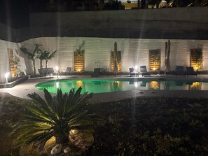 A nighttime pool area with lounge chairs and wall-mounted lights. - B&B Villa Gabry  (Capo d'Orlando)