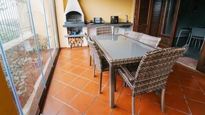 A patio with a glass door, wicker chairs, a table, and a wood-burning stove. - B&B Villa Gabry  (Capo d'Orlando)