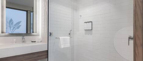 Un baño moderno con ducha de vidrio, un espejo grande y un mueble de tocador con encimera de madera.