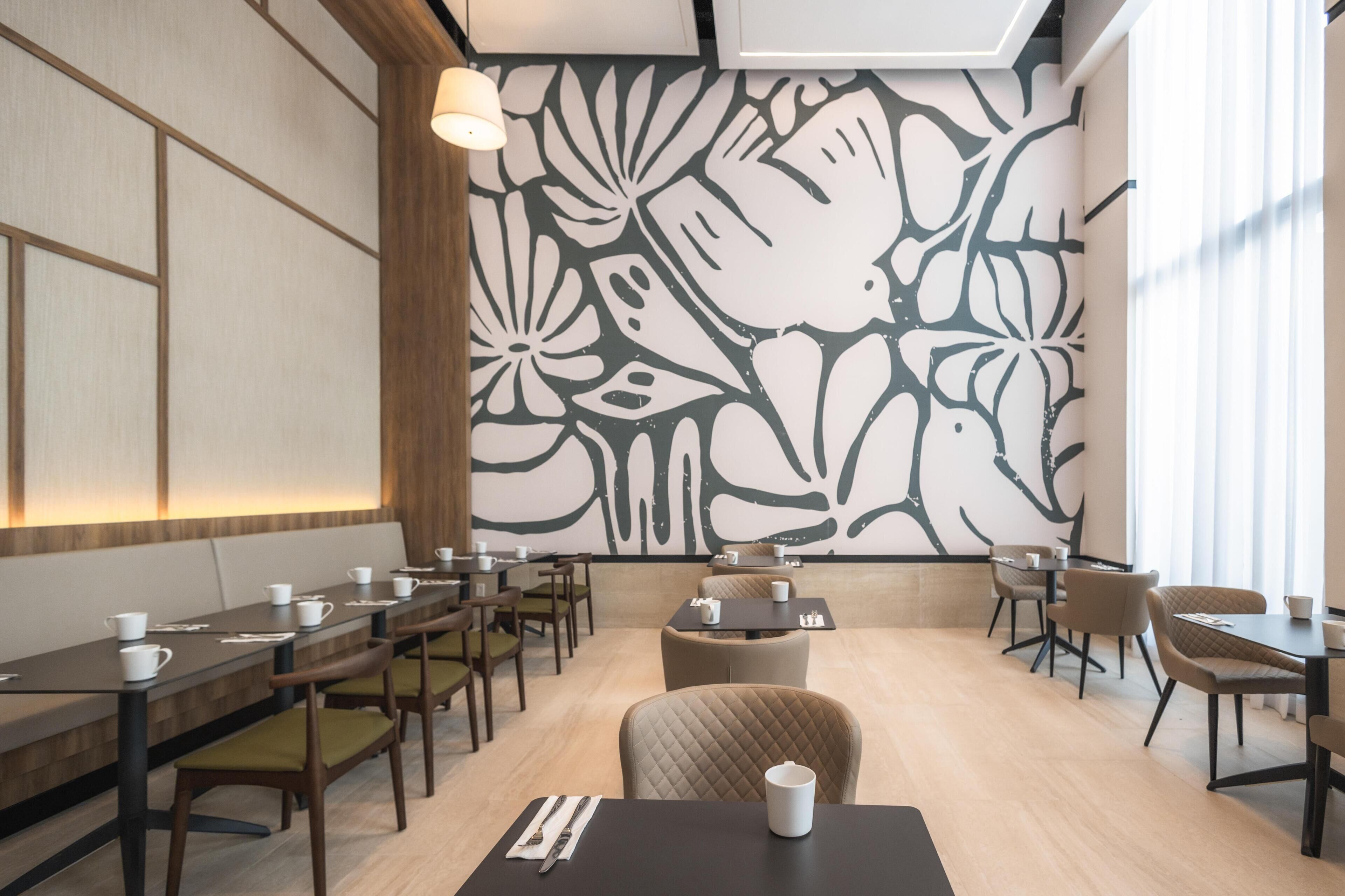 Un comedor moderno con una mesa larga, sillas y una pared decorativa con estampado floral.