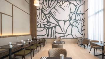 Un comedor moderno con una mesa larga, sillas y una pared decorativa con estampado floral.