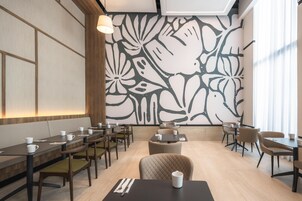 Un comedor moderno con una mesa larga, sillas y una pared decorativa con estampado floral.