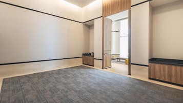 Una habitación amplia con piso alfombrado, armarios de madera y un espejo.