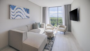 Ein modernes Wohnzimmer mit einer Eckcouch, zwei Sesseln, einem kleinen runden Tisch und einem Flachbildfernseher.