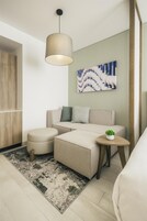 Una sala moderna con un sofá, un reposapiés y una mesita auxiliar con una planta.