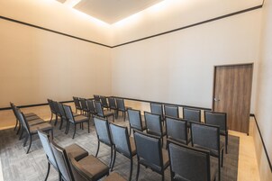 Una sala conferenze con file di sedie e una porta in legno.