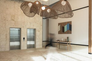 Un hall espacioso con un estampado de tablero de ajedrez en el suelo, una lámpara de araña moderna y una obra de arte abstracto colgada en la pared.