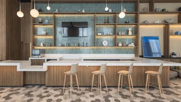 A modern kitchen with a bar area, wooden cabinetry, and a tiled backsplash.