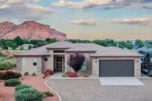 A two-story house with a stone facade, a garage, and a driveway leading to the entrance.