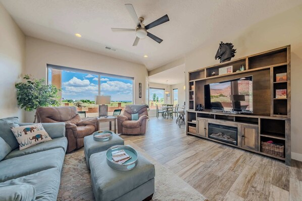 A spacious living room with a large TV, comfortable seating, and a fireplace.