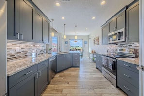A modern kitchen with dark cabinets, a granite countertop, and stainless steel appliances.