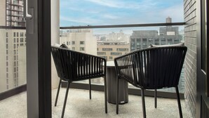 A balcony with two chairs and a table, overlooking a cityscape with buildings. - The Livingston, part of JdV by Hyatt (Brooklyn)