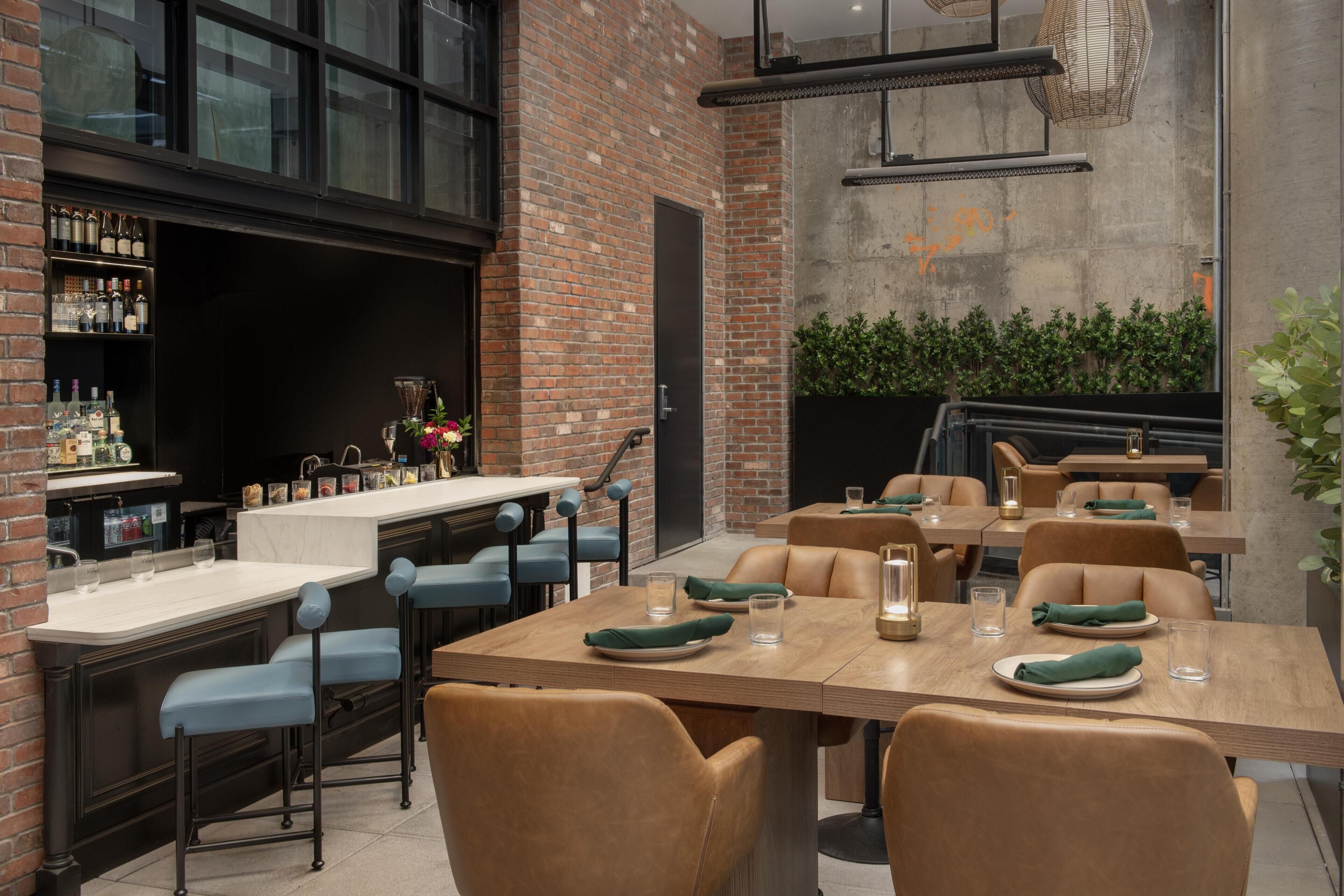 A modern restaurant with brick walls, a bar area, and seating for guests.