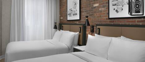 Une chambre d’hôtel avec deux lits, un mur en briques et deux tableaux encadrés.