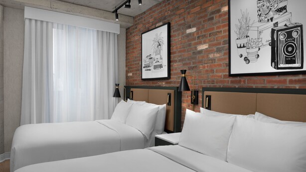 A hotel room with two beds, a brick wall, and two framed pictures. - The Livingston, part of JdV by Hyatt (Brooklyn)